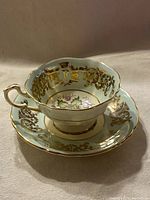 Teacup and saucer set showing the gold gilt interior decoration and floral maple leaf pattern.