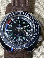 Front view of watch showing black dial, green luminous markers and tachymetre bezel