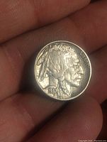 Obverse side of 1937 Buffalo Nickel held in hand, showing Native American profile and date 1937