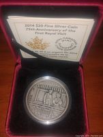 Photo of silver coin in red display case with certificate describing the 75th anniversary of the first royal visit to Canada and denomination $20.