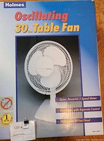 Box front showing Holmes brand oscillating table fan, 30cm with product image and features like 3-speed motor, separate control, adjustable fan head.