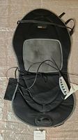 Black Obus Form massage mat laid out flat showing gray padded back area, wired remote control on right side pocket, power cords visible.