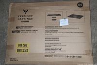 Photo of box front showing Vermont Castings Vanguard branding, product name '4-Burner Propane Barbecue Grease Drawer Assembly,' and box numbered as 2 of 2. Unopened original packaging with storage wear.