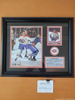 Framed Jean Beliveau poster featuring two photos, Canadiens logo, and stats card in black frame.