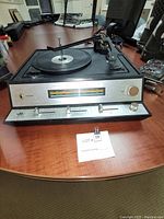 Front view showing analog tuner dials, color display for frequency, wood paneling on the sides, and controls on the front panel.