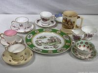 Full view of the complete lot showing 5 distinct teacups and saucers, dinner plate, cream and sugar bowls, tavern mug, and one extra saucer.