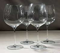 Four clear balloon wine glasses arranged in a line.