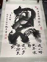 Full view showing large calligraphy characters in black ink on white paper, mounted on light green silk fabric with wooden dowel visible at top.
