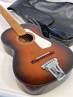 Photo showing the sunburst finish midsize Arwin guitar with white pickguard, wooden neck, and included black vinyl zippered case.