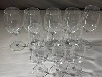 Full view of all eleven Riedel glasses arranged in rows on a neutral fabric background.