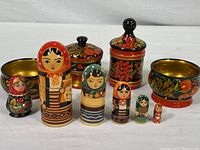 Full set displayed including seven Russian nesting dolls, two covered jars with lids, two decorated bowls, and a refrigerator magnet on a white background.
