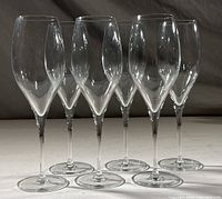 Six clear Schott Zwiesel wine glasses arranged upright on a surface, showing tall stems and elongated bowls.