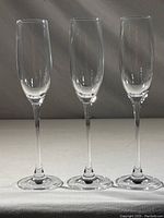 Three clear Lenox champagne flutes standing side by side from front view showing full length and slender shape.