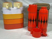 Front and side view of 1970s color-blocked dual hot pot and two red Aladdin insulated glass thermoses with cups and faux suede zippered carrier