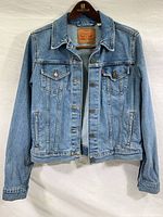 Full front view of the vintage Levi’s denim jacket showing button closures, classic denim blue color with signs of light wear.