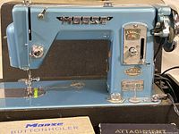 Close-up on front and needle area of the blue Morse sewing machine with thread in place.