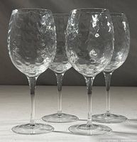 Front view showing four clear glass wine goblets with a rounded optic pattern on the bowl.