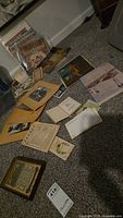 Overview of assorted Americana ephemera on floor showing postcards, photos, documents, and magazines.