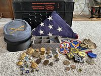 Full layout showing gray Civil War style cap, folded American flag, various pins, badges, and patches.