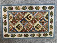 Top view of the front of the area rug showing the floral sculpted design and multicolor floral and leaf pattern with blue border.