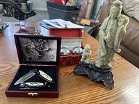 Figurine, Baoding stress balls and hunting knife set arranged on a table.