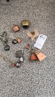 Photo showing various assorted metal bells on carpeted floor, includes copper-colored and silver-colored bells with diverse sizes.