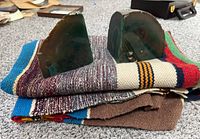 Photo showing the pair of green stone bookends placed on a folded multi-colored woolen blanket on carpeted floor.