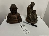 Photo of both brass items: Beatrice bookend bust on left, monk figurine on right, black marker for scale