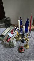 Photo showing assorted candle holders of brass, pewter, glass and metal, assorted candles, and vintage candle lantern.