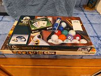 Overview of all items showing the Golfer's Putter Pool, Canasta game, two decks of cards, colored golf balls and the tube with numbered discs.