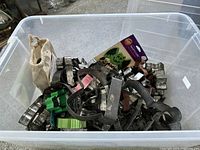 Plastic bin filled with assorted metal and plastic cookie cutters, fabric pouch, various shapes.