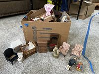 General overview of box of doll furniture and assembled pieces arranged on carpet