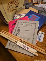 Photo of the drumsticks, practice pad, and drum instructional books on a wooden table.