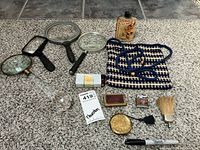 Overview photo showing the full collection including 4 magnifying glasses, small vintage lighter, metal shaving brush, two metal makeup compacts, beaded handbag, hairpins, vial, and other small accessories.