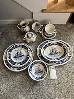 Front view of the full set showing plates, bowls, sugar bowl, pitcher, and tea cups with saucers on carpet.