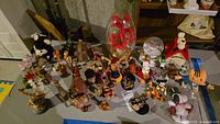 Photo of assorted figurines including Snoopy characters, elephants, bears, dogs, castanets, and a floral display in glass.