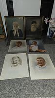 Framed and unframed vintage portrait pictures of grandparents and young boys on floor