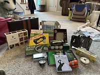 Overview photo showing assortment of golf accessories, books, golf ball markers, light up golf balls, tees, puzzle, backgammon set, photo cards, picture frame, and other items spread out on floor.