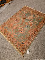 Rectangular handwoven rug with detailed traditional pattern on floor, showing overall design and color.