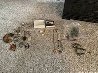 Wide view of assorted jewelry including earrings, necklaces, and pins laid out on carpet.