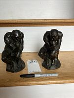Front view of the pair of small bronze bookends modeled after Rodin's The Thinker with a Sharpie marker for scale