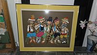 Full view of framed print showing five musicians in colorful attire playing various instruments, with a brown background and yellow mat.