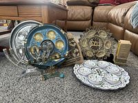 Overview of all Judaica items including two menorahs, three seder plates, fabric seder toy bags, metal Judaica art, Dreidel, and Dead Sea Scrolls representation.