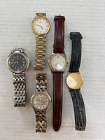 Five men's watches in a row showing bands and faces: Paolo two-tone stainless steel, Levenger leather, Seiko Quartz with damaged glass and missing buckle band, Swiss Army with stainless steel band, and another Seiko Quartz with gold-tone case.