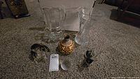 Large crystal vase, 10-inch pitcher, glass polar bear figurine, crystal reindeer missing an ear, Waterford crystal golf ball, and ceramic vase arranged on carpet.
