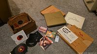 Wide angled shot showing two RCA Victor Glenn Miller limited edition album boxes with vintage vinyl records and sleeves gathered on carpeted floor alongside smaller records and cassette tape sets
