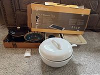 Overview of all items including Crate and Barrel white soup tureen with lid and ladle, brown glaze soup crock, VillaWare Uno warming tray in box, beige Mikasa Italian Countryside plate, and assortment of ceramic bowls and casseroles.