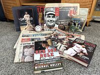 Photo of the books including The Kid, Big Bam, Red Sox Rule, and Deep Drive arranged with a baseball, a baseball-themed Stein, newspapers, and a Times magazine.