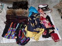 Overview photo of assorted scarves of different materials and one ladies shirt laid out on floor