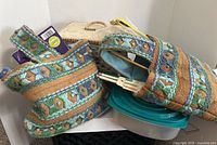 Two vintage sewing and knitting bags with colorful woven pattern, with various sewing supplies and containers nearby.